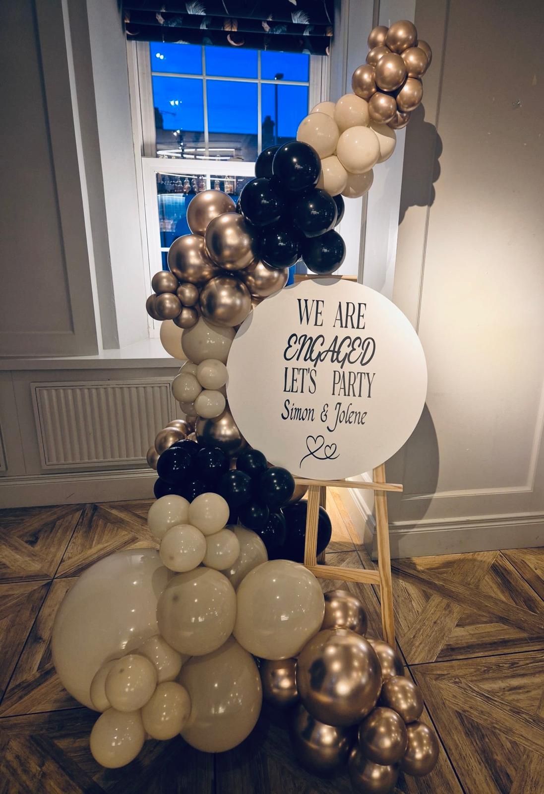 Engagement party balloon arch in gold, black and cream with bespoke sign at a venue in County Down