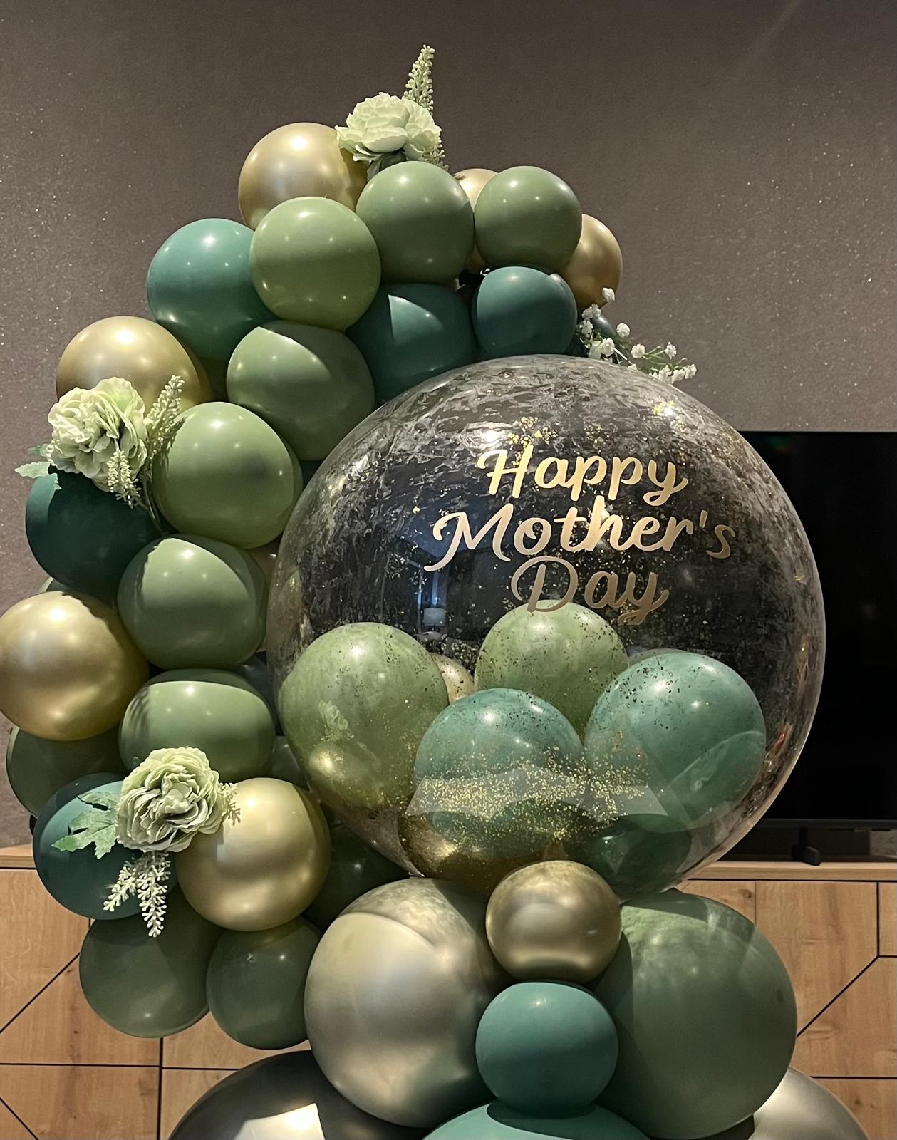 Sage green and gold Mother's Day balloon arch close-up with glitter bubble in Newtownards